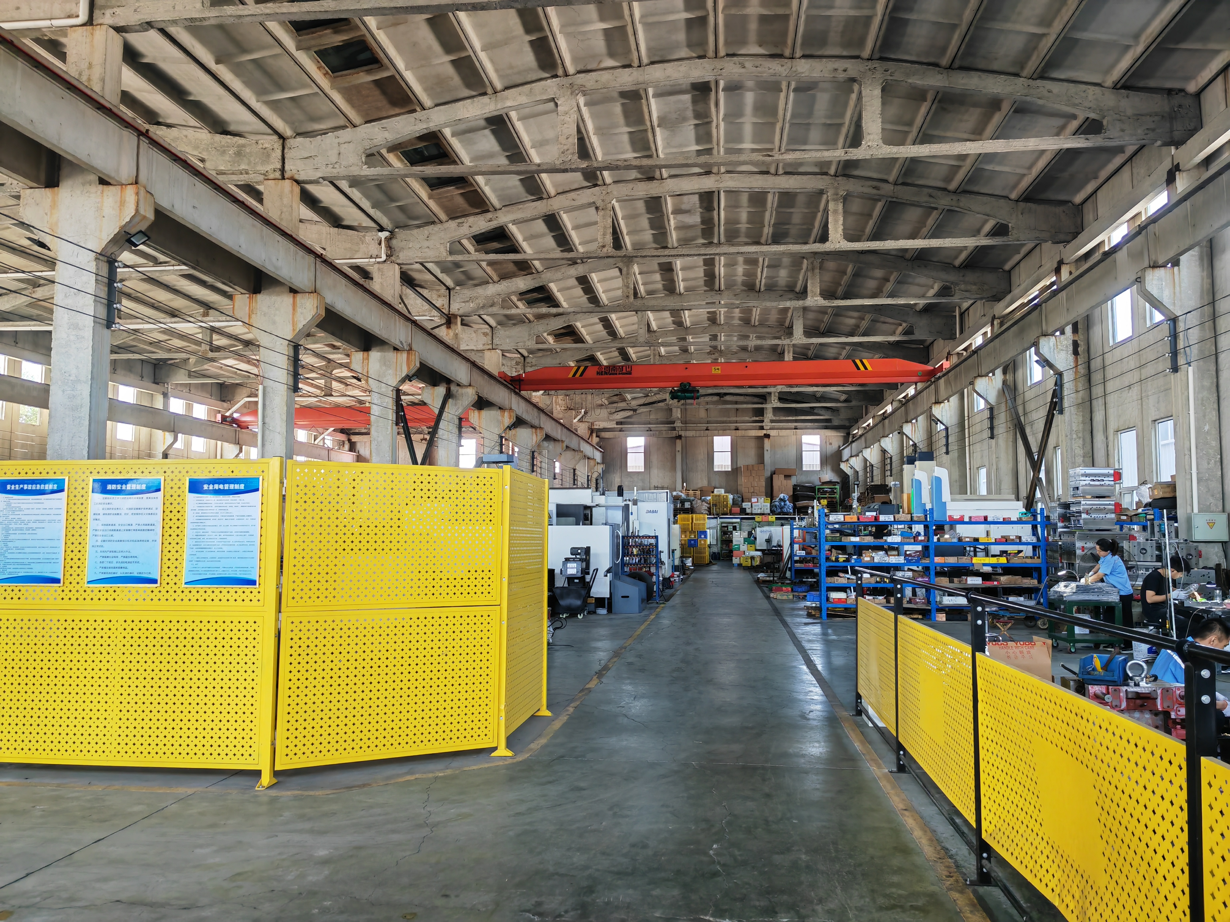 Factory aisle with an overhead crane, CNC machines and parts shelving inside the Qingdao workshop